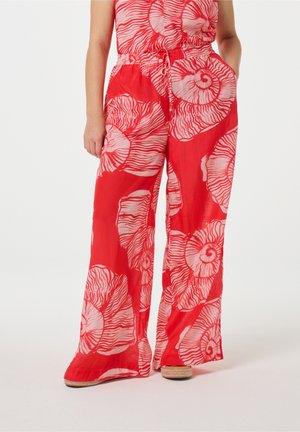 Rode broek met brede pijpen, grote lichtroze schelpenprint, taille met trekkoord en zakken, gecombineerd met geweven espadrilles.