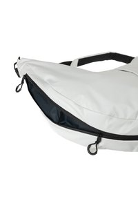 Witte nylon tas met een gebogen vorm, uitgerust met een zwarte rits en treklip, en een contrasterende donkere binnenvoering.