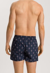 Pantaloni da bagno blu navy con un motivo a diamante ripetuto in rosa e bianco, dotati di una vita elastica e di un fit morbido.