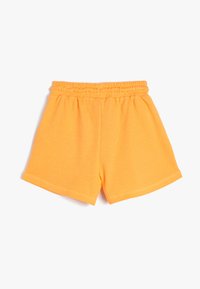 Orange bomuldsbukser med ribbet tekstur, elastisk talje og lige pasform. Har simpel syning langs kanten.