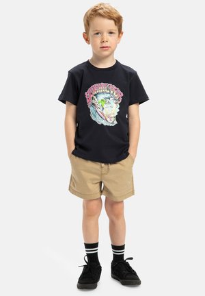 Czarny bawełniany t-shirt z kolorową grafiką fali, w połączeniu z beżowymi szortami. Dziecko ma na sobie czarne buty i paskowane czarne i białe skarpetki.