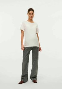 Camiseta blanca de manga corta combinada con pantalones de pierna ancha grises. La tela parece suave, con un ajuste casual y detalles sutiles y texturizados.