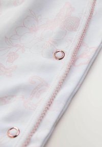 Květinová látka v bílé a jemně růžové barvě s růžovým prošitím. Obsahuje stříbrný druk na švu pro zapínání.