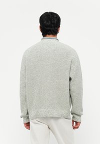 Light gray knit sweater with a textured finish, ribbed cuffs, and hem. Casual oversized fit with a round neck and long sleeves.