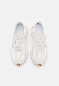 Paire de baskets New Balance blanches et roses claires avec lacets, vues de dessus sur un fond blanc uni.