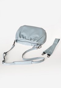 Hellblaue Lederhandtasche mit gerafftem oberen Teil, Reißverschluss und verstellbaren Trägern. Enthält zwei zusätzliche Trageoptionen in passender Farbe.