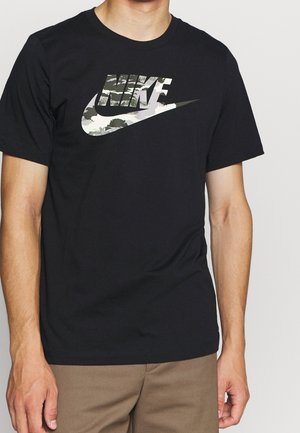 Camiseta negra de algodón con un gran logo de Nike estampado en camuflaje. Mangas cortas, cuello redondo y corte relajado.