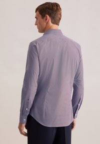 Langsleeve, getailleerd shirt in marineblauw met een wit geometrisch patroon; knoopmanchetten; zachte, gladde stof; gebogen onderkant met rugpasdetail.
