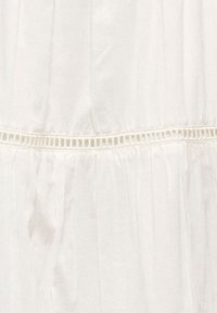Tissu blanc avec une bordure de dentelle décorative horizontale et des détails froncés sous la bordure.