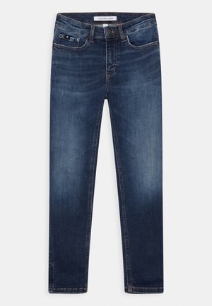 Vaqueros ajustados de color azul oscuro con un ligero desgaste en los muslos, bolsillos delanteros, cierre con botón y etiqueta de Calvin Klein Jeans en la cintura.