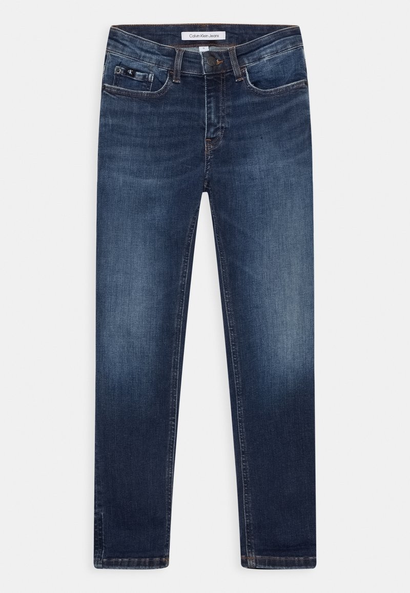 Vaqueros ajustados de color azul oscuro con un ligero desgaste en los muslos, bolsillos delanteros, cierre con botón y etiqueta de Calvin Klein Jeans en la cintura.