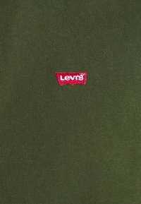 T-shirt verde oliva con texture a coste, con logo Levi's rosso ricamato sul lato sinistro del petto. Design semplice e casual.
