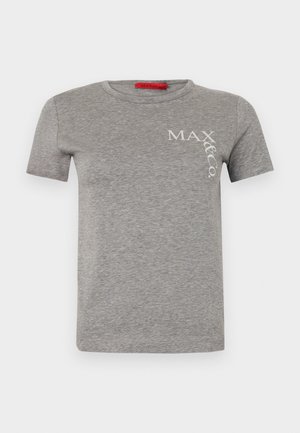 T-shirt en coton gris avec du texte blanc, associé à un short rayé rose et blanc. Un sac à dos noir et des chaussettes grises avec des chaussures noires complètent le look.