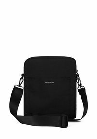 Černá crossbody taška vyrobená z odolného materiálu, má obdélníkový tvar, nastavitelný popruh, přední kapsu a minimalistický logotyp.
