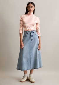 Rööbastega roosa ja valge kõrge kaelusega särk, millele on sobitatud helesinine denimpikk seelik. Kleidil on lõdva lõikega ja valged tenniseketega, millel on beežid tallad.