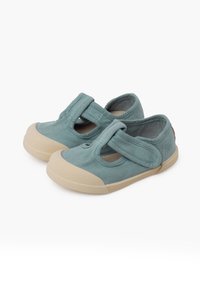 Blaue Segeltuchschuhe mit runder Zehe und beigefarbenem Gummisohle. Sie verfügen über Klettverschlüsse und ein Ausstanzungsdesign zur Belüftung.