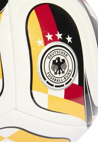 Primo piano di un pannello di un pallone da calcio bianco che presenta il logo del Deutscher Fußball-Bund, quattro stelle e i colori della bandiera tedesca: nero, rosso e giallo.