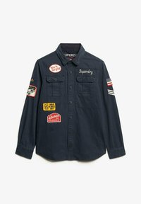 Navy button-up shirt featuring two chest pockets, various colorful embroidered patches, and striped American flag accent on the sleeve.