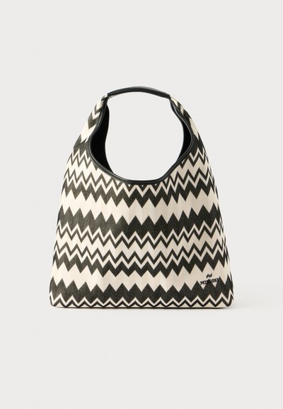 Sac hobo en motif zigzag noir et blanc, fabriqué en tissu texturé avec une poignée arrondie et un petit logo en bas à droite.