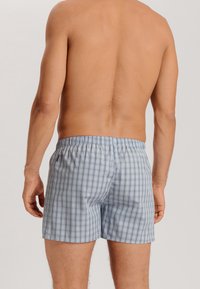 Boxers à carreaux bleu clair avec un taille élastique, présentant une texture de tissu douce et un motif en plaid simple.