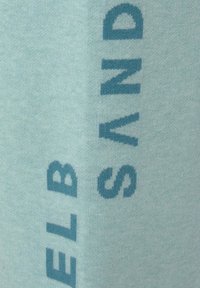 Lichtblauwe stof met gedurfde, donkerblauwe tekst in een pixelontwerp. Zachte textuur, verticale oriëntatie en duidelijke leesbaarheid van de letters.