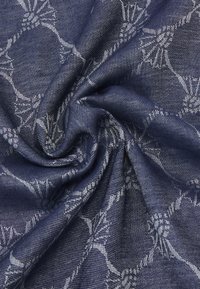 Navyblauwe stof met een gestructureerde afwerking, voorzien van een bloemenpatroon in lichtgrijs, gedrapeerd om de zachtheid en het complexe ontwerp te tonen.