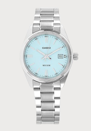 Srebrni metalni Casio ručni sat sa svijetloplavim brojčanikom, tri kazaljke koje pokazuju 10:09:03, prozor za datum na 3 sata i vodootpornost do 50 metara.