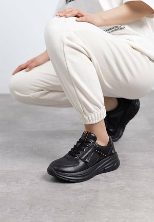 Sneakers neri in pelle, con una tomaia strutturata, zip decorativa e una suola spessa con un motivo scolpito.
