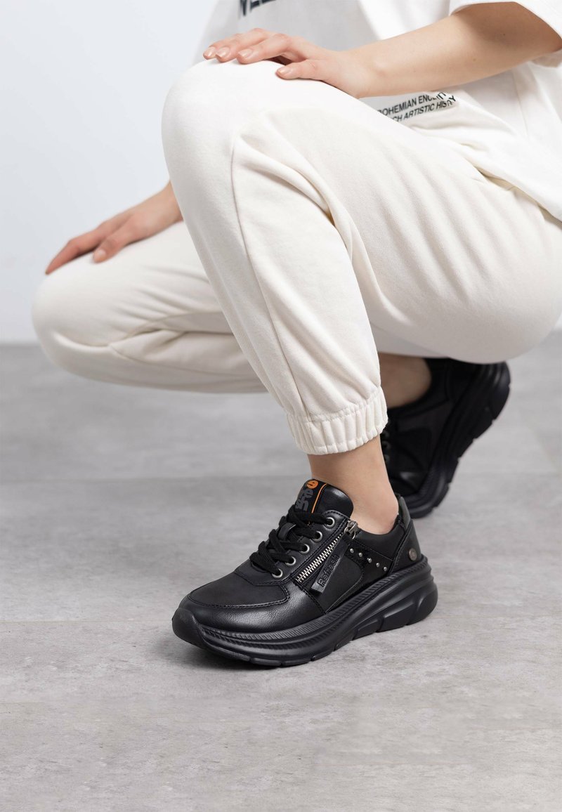 Sneakers neri in pelle, con una tomaia strutturata, zip decorativa e una suola spessa con un motivo scolpito.