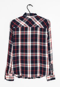 Marineblauw geruit shirt met rode, witte en grijze blokken, lange mouwen, kraag en knoopmanchetten. Gladde stof, hangt aan een zwarte haak.