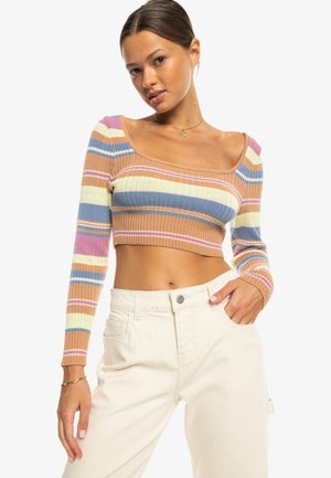 Pull cropped côtelé à manches longues, avec des rayures horizontales dans des couleurs pastel de rose, bleu, jaune et beige. Pantalons blancs taille haute.