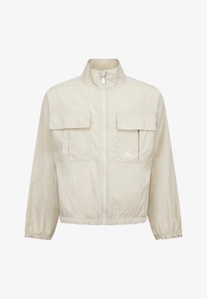 Cremefarbene Zip-Jacke aus leichtem Material, mit zwei Taschen vorne, elastischen Bündchen und einem weißen Logo-Detail auf der Brust.
