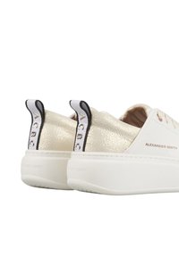 Sneaker bianche con accenti metallici dorati testurizzati, design con lacci, tacchetti neri a contrasto sul tallone e branding in rilievo sul lato.