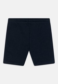 Navyblå bomullsshorts med elastisk midja, flat söm och med-lår längd, uppvisade mot en vit bakgrund.
