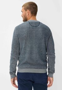 Strikket sweater i marineblå med en tekstureret overflade og grå kant ved kraven og manchetterne. Har ribbestrikket detalje og rund halsudskæring.