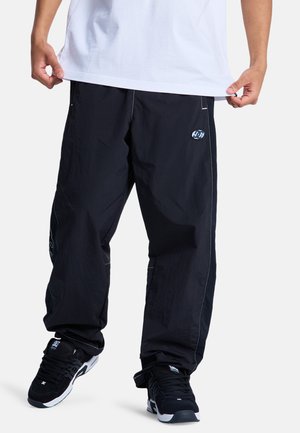 Luźne spodnie w kolorze czarnym, wykonane z teksturowanej tkaniny, z białym przeszyciem i bocznymi kieszeniami. Logo umieszczone po lewej stronie.