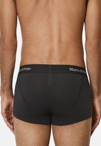 Schwarze Baumwollboxershorts mit einem elastischen Bund mit Logo. Sie verfügen über ein enganliegendes Design und eine glatte Textur, die die Konturen des Körpers betont.