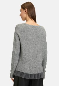 Pull en tricot gris avec une coupe décontractée, doté d'un large col et d'un ourlet en superposition de volants transparents. Tissu texturé au toucher doux.