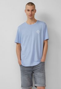 Lichtblauwe katoen t-shirt met een ronde hals en korte mouwen, met een klein wit logo bedrukt op de linkerborst.