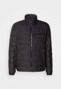 Zwarte pufferjack met een hoge kraag, horizontale naden, rits aan de voorkant en een leren patch met het "BOSS"-logo op de borst.