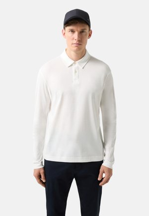 Langærmet hvid polo med knapkrave, lavet af glat stof; har et lille logo på brystet og en afslappet pasform.
