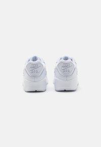 Baskets blanches Nike Air, avec une tige en cuir lisse, un col rembourré et un logo embossé au talon, dotées d'une forme arrondie et d'une semelle en caoutchouc.