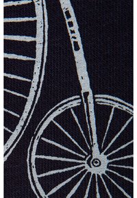 Tissu texturé bleu avec des motifs de roues de bicyclette blanches, montrant des rayons et des jantes détaillés dans un motif répétitif.