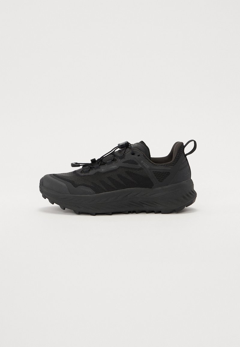 Baskets de sport noires avec une tige en maille texturée, une épaisse semelle en caoutchouc et des lacets élastiques pour un maintien sécurisé. Comprend un talon et des côtés renforcés.