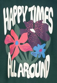 Groene stof met een kleurrijk bloemenpatroon en grote witte tekst die "HAPPY TIMES ALL AROUND" zegt, met een nadruk op vibrante roze, paarse en blauwe bloemen.