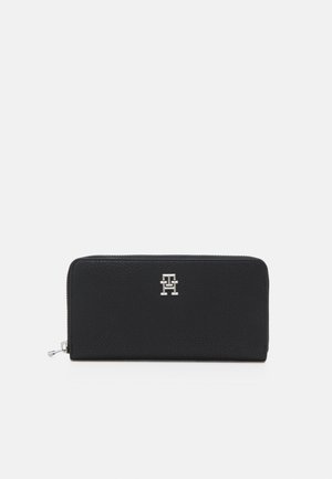 Black leather wallet with a textured finish, featuring a silver logo on the front and a zip closure along the top edge.