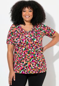 Tričko s výstřihem do V v pestrém květinovém vzoru, obsahující růžové, zelené a černé odstíny. Vyrobeno z měkké, elastické látky s krátkým rukávem.