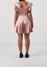 Pink satin dress with short ruffled sleeves, v-back, and flared skirt. Finished with a central zipper at the back. Black shoes worn.