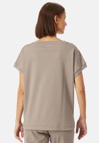 Lichtbruin shirt met korte mouwen, een ontspannen pasvorm, ronde halslijn en opgerolde mouwuiteinden. Gladde stof met minimale stikdetails.