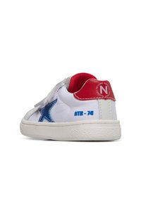 Sneakers bianchi con dettagli a stella blu, accenti rossi e grigi, e chiusura in velcro. Presentano una suola texturizzata e la scritta "NTR-74" stampata sul tallone.